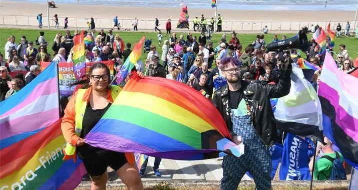 A number of people waving flags on Portrush's West Strand beach for the town's first ever pride parade in 2023.