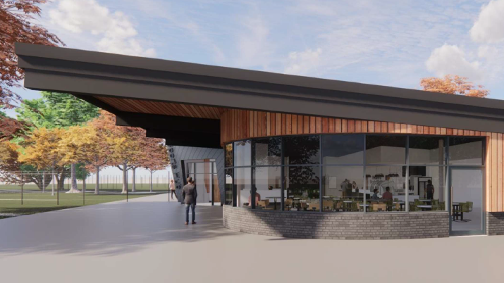 A CGI image of a pavilion building. It has a sloping roof and wooden panelling outside. It has large glass windows which show a cafe inside the building. Trees and a sports pitch can be seen off to the left.