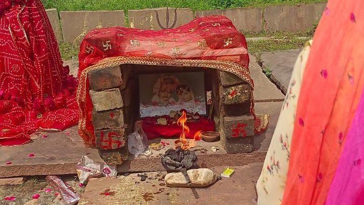 A lamp is lighted in front of the photograph of Roop and her husband at the place where they were cremated