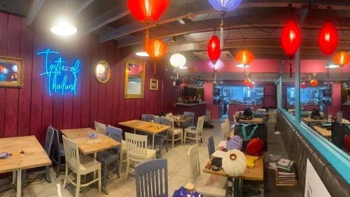 Image of what the restaurant looks like inside- with white tables and chairs and colourful lanterns on the roof