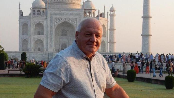 Gareth Delbridge in front of the Taj Mahal. There is a walking up a path crowd behind him