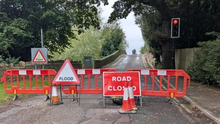 Red road blocks, flood and road closed signs seal off a bridge