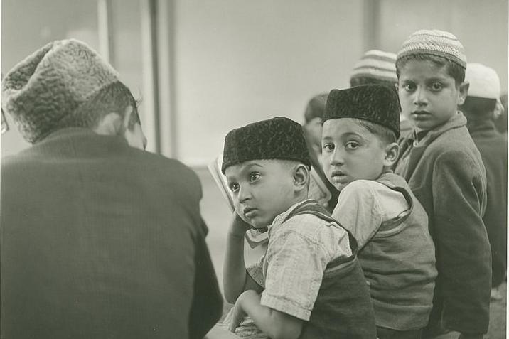 A group of children with various religious hats on turn to look at the camera  