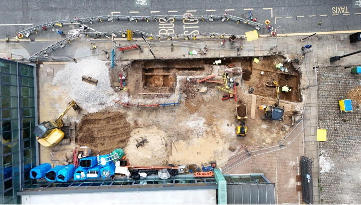 The remains of a Roman road can be seen by the side of a road and a bus stop in Manchester city centre.