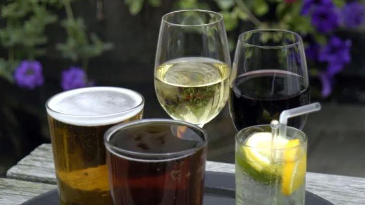 Glasses containing alcoholic drinks on a wooden outdoor table