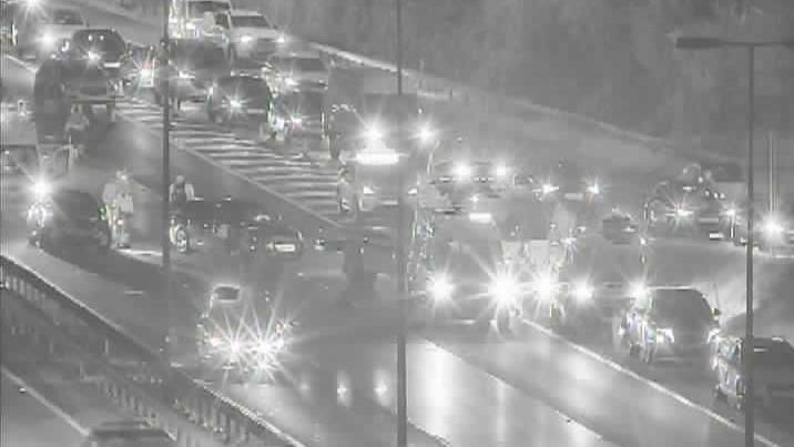 A night-time CCTV image of cars queuing at junction five of the M40. There are cars pulled over and people standing in the slip road off the motorway.
