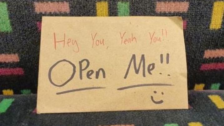 A brown envelope reads: "Hey you, yeah you!! Open me!!".