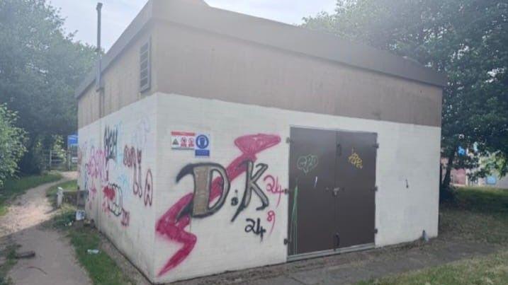 The building before the mural was painted, with bright red spray paint on one side and initials on top