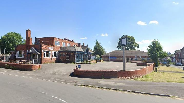 A Google Map photo of the Red Lion pub on Batley Road. The venue has a large car park and is located next to a busy road.