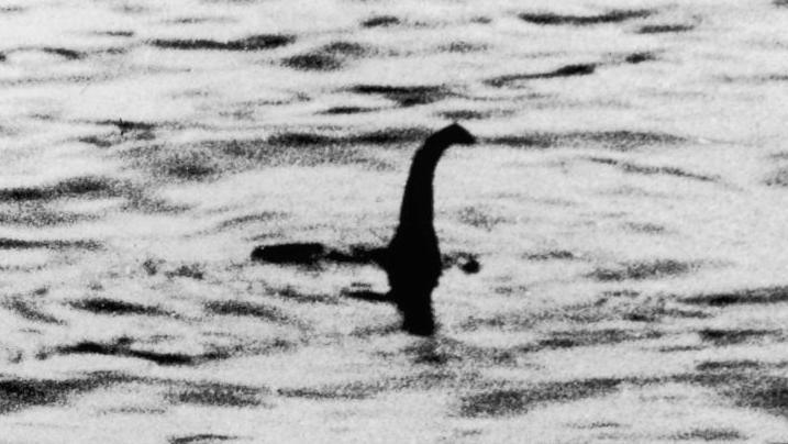 A black and white faked photograph of the Loch Ness Monster that shows a long neck and head coming out of the water.