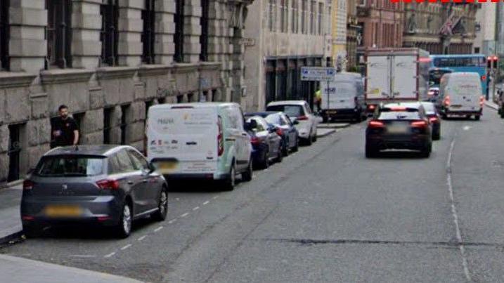 Several cars and a van can be seen parked in a bay on North John Street in Liverpool city centre.