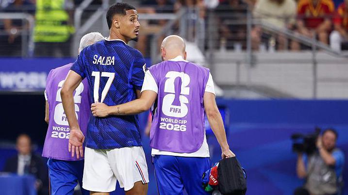 William Saliba is helped from the field by a physio during France's World Cup semi-final defeat by Spain