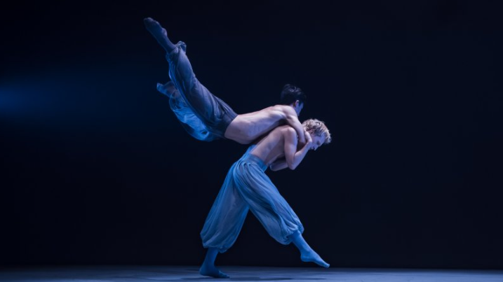 Two dancer performing under blue lights.