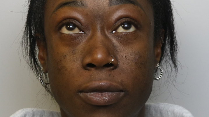 A woman facing a camera, looking up, wearing two silver hoop earrings.