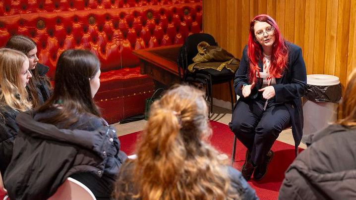 Carmen yn siarad gyda disgyblion ysgol mewn digwyddiad yn Nhŷ'r Arglwyddi