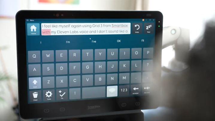 A close-up image of a computer screen with a digital keyboard on it, which Sarah uses to build words using eye-gaze technology. The screen reads "I feel like myself again using Grid 3 from Smartbox with my Eleven Labs voice and I don't sound like a..."