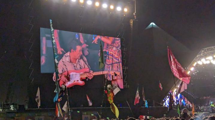 Michael J Fox on the Pyramid Stage at Glastonbury Festival, playing a guitar with Coldplay.