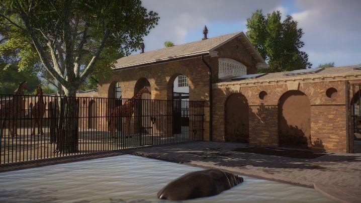 A digital image of the giraffe house, a brick structure with railings and a giraffe standing in the courtyard area in front. A hippo wallowing in a pool is in the foreground.