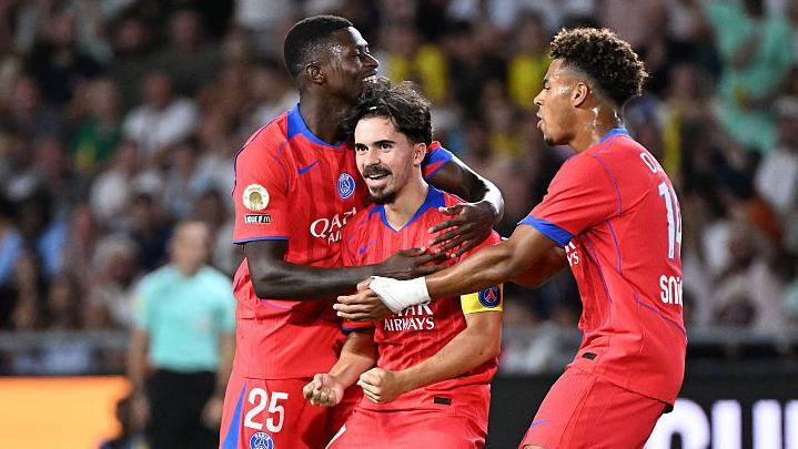 Vitinha celebrating with Nuno Mendes and Desire Doue in red third kit