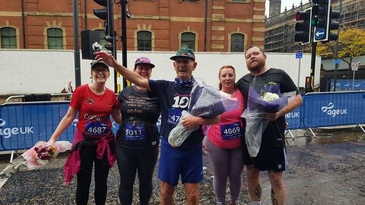 Five runners celebrate the end of a race with flowers