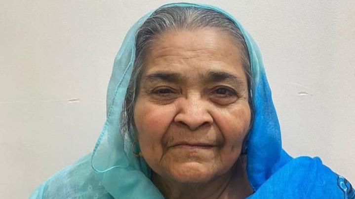 The head of an elderly lady wearing a blue headscarf