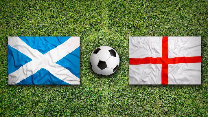 Flags of Scotland and England with a football on a football pitch.
