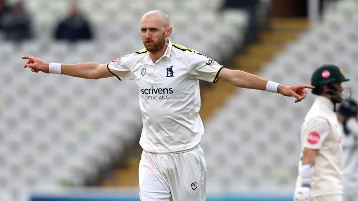 Olly Hannon-Dalby stretches both arms out in celebration at taking a wicket