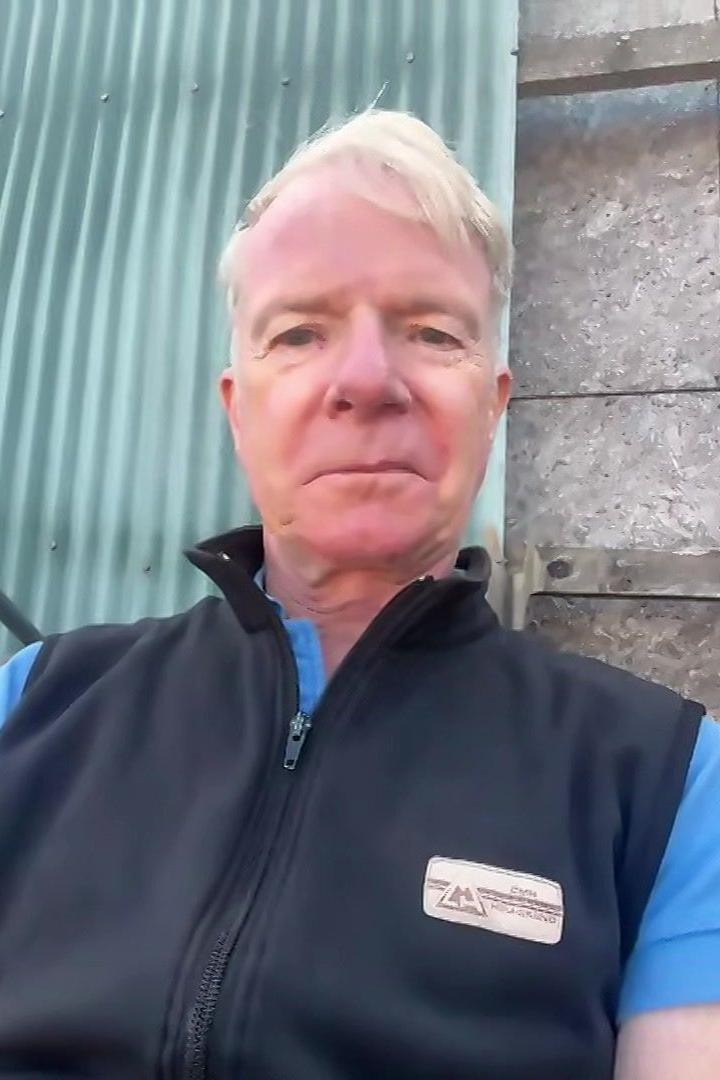 Edward, a man with grey hair and blue eyes. He is wearing a navy shell jacket over a blue t shirt.