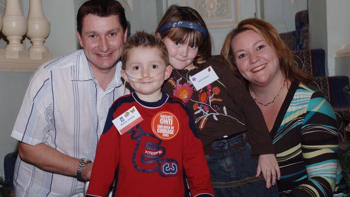 A family of a man, woman and two children, a young girl and boy. The boy is wearing a red top and has a tube which goes into his nose. Chris, Matthew, Laura and Lisa Hayden-Johnson