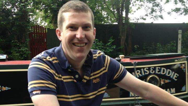 Alex Prentice with short brown hair standing beside a narrowboat