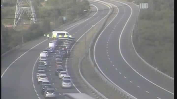 A traffic camera picture of the M49, showing traffic being held by police. A row of cars is shown queued up behind a police van parked sideways on the road. 