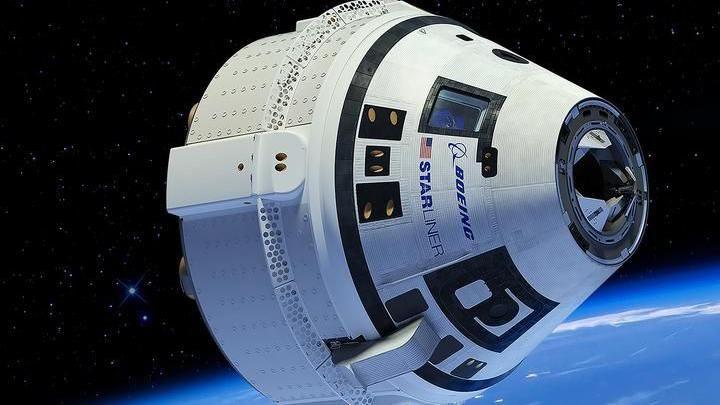 The Starliner capsule in orbit. The edge of the Earth can be seen as a bluish haze in the bottom right hand part of the frame with the white conical capsule with a Boeing logo in the foreground.