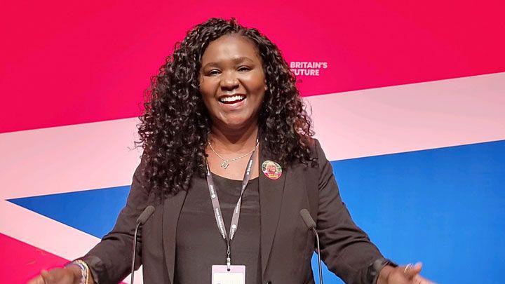 Marianne Kimani standing at a lectern smiling