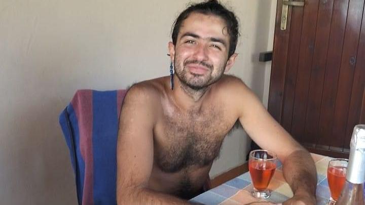 A man sitting topless at a dining table