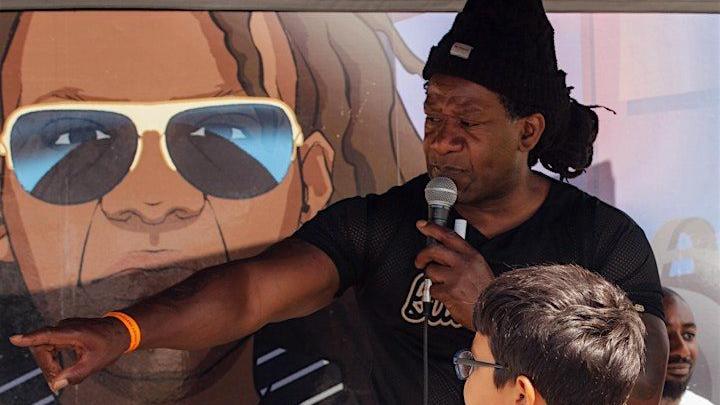 Dave ‘DJ Redlocz’ Okwesia standing in front of children with a microphone