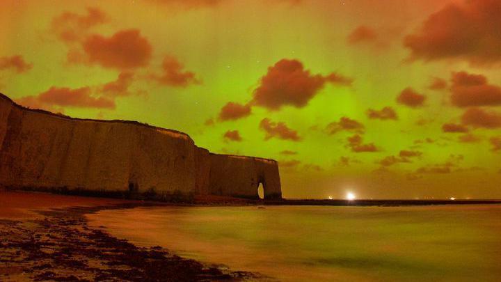 White cliffs yellow and orange under the Northern Lights. 