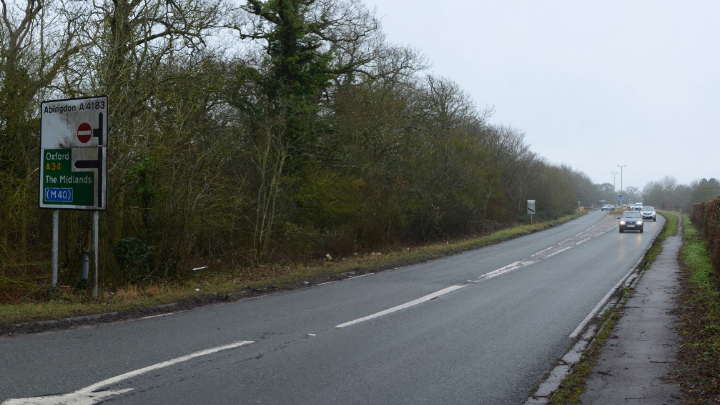 an a-road on a drizzly day, the cars have their headlights on