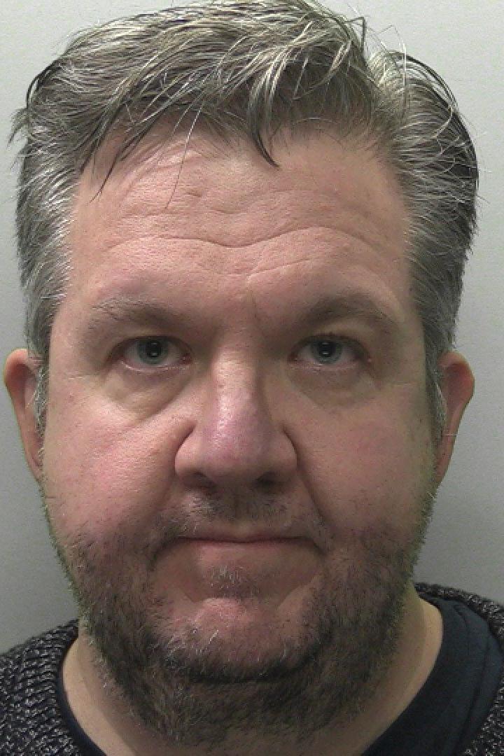 A custody picture of Neil Hopper. He has grey hair and is looking into the camera with a blank expression.