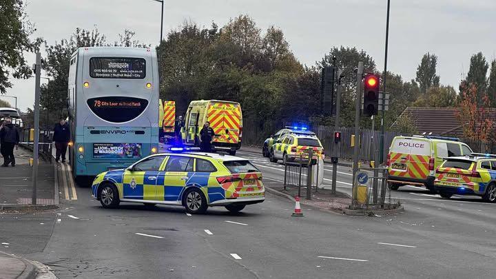 Several police vehicles have closed off Bobbers Mill Bridge, near Aspley Lane in Nottingham. A double-decker bus is situated on the left of the road.