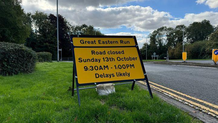 A yellow road closure sign placed on the side of the road.