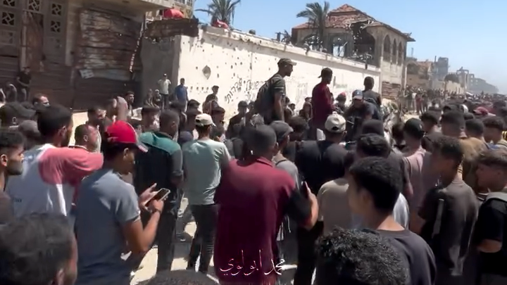 A screengrab from a verified video showing a crowd walking alongside a horse and cart carrying bodies