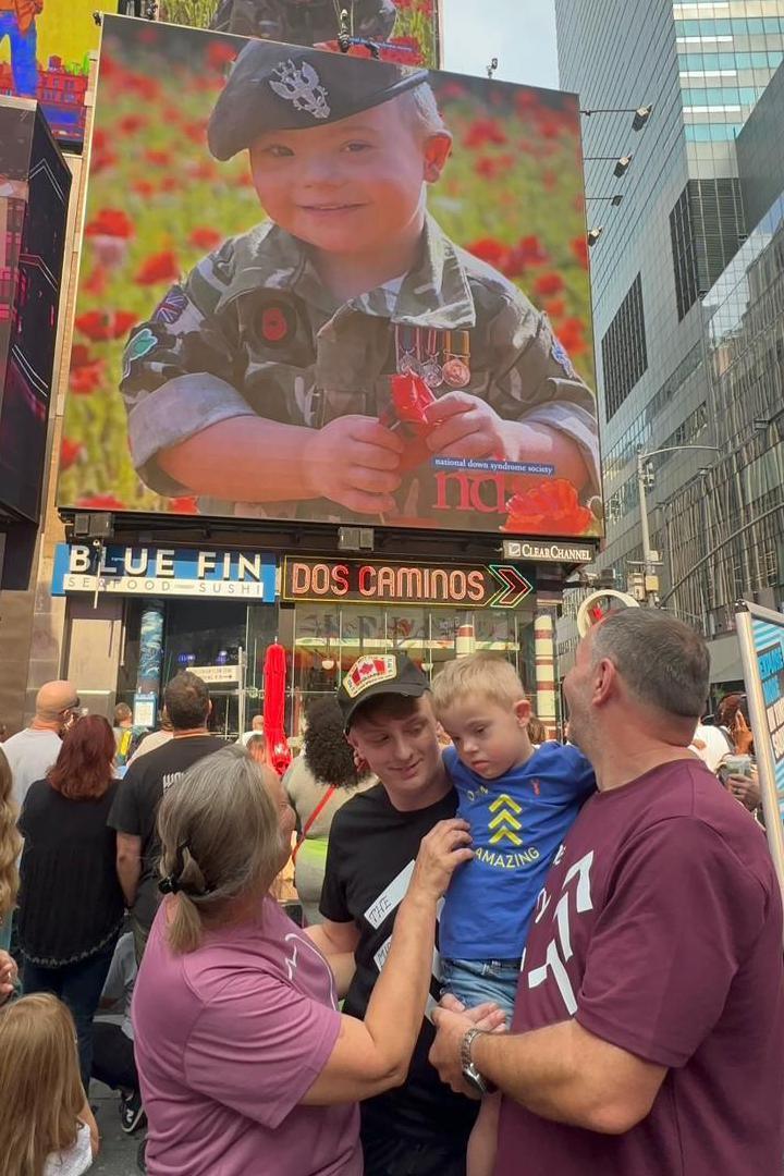 Ethan is being held by his parents as they all watch the moment his photo appears on the big screen