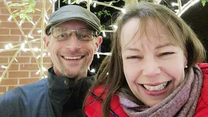 Richard Rowe wearing a dark coat, glasses and a flat cap next to his wife, Rachel, who is wearing a red coat and a pink scarf.