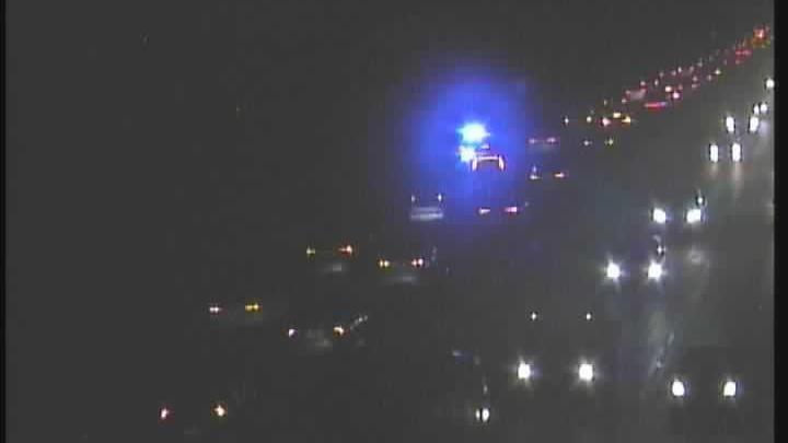 A traffic camera picture of queuing cars on the M32. It is very dark, and all you can see are headlights. A blue flashing light is visible on the hard shoulder. 