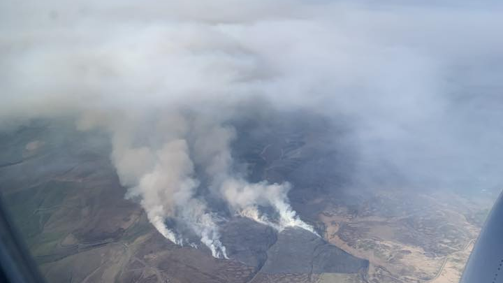 An aerial view of a moorland fire, with smoke seen rising from the ground