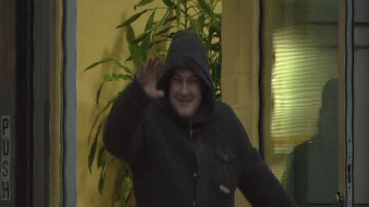 Ryan Leslie leaving court in 2011. He is wearing a black coat with the hood up, waving and smiling at the camera.