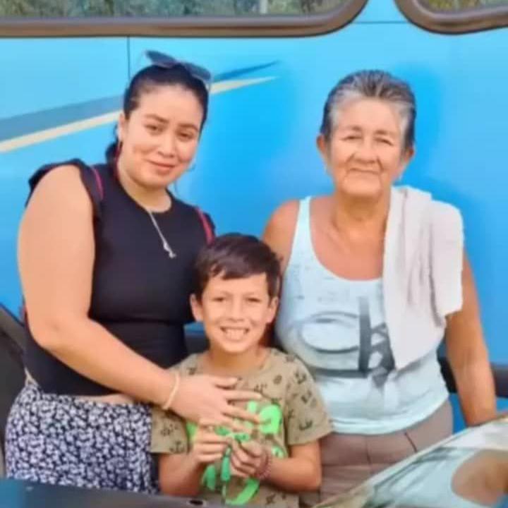 Family photo of a mother embracing a boy beside his grandmother