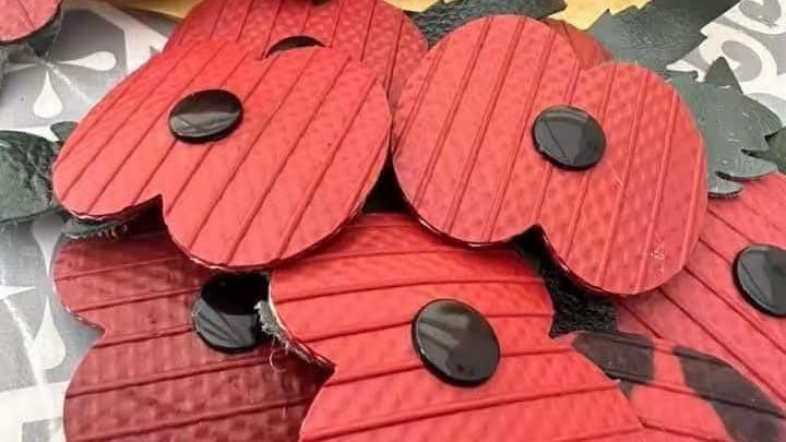 A heap of red handmade poppies piled on top of each other