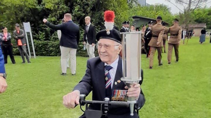 Jack Hearn on a scooter with marching soldiers behind