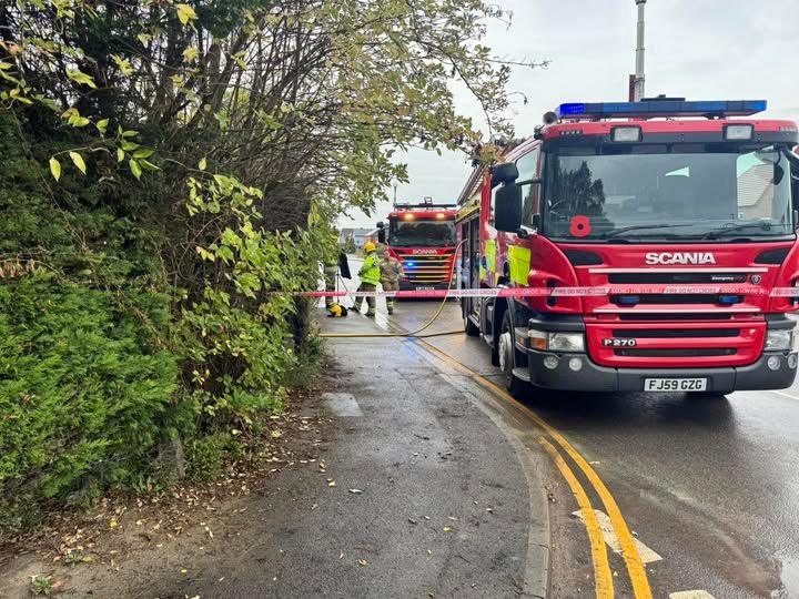 A fire cordon across a pavement and two fire engines parked within the cordon.